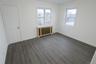 Unfurnished bedroom featuring radiator heating unit and wood finished floors
