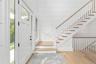Entrance foyer with stairway, light wood-type flooring, and wood walls