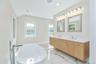 Full bathroom featuring a soaking tub, light marble finish floors, double vanity, and recessed lighting