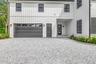 Modern inspired farmhouse with board and batten siding, gravel driveway, covered porch, and an attached garage