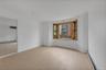Interior space featuring wood-finish flooring, a three-panel bay window with natural wood trim, and recessed ceiling lighting