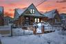 Bungalow with a gate, a fenced front yard, covered porch, brick siding, and stone siding
