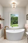 Bathroom featuring a soaking tub, baseboards, and a chandelier