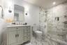 Full bathroom featuring tiled shower, vanity, toilet, and baseboards