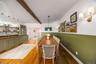 Dining space featuring wainscoting, wood finished floors, beam ceiling, and bar area