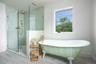 Full bath with a freestanding tub, a walk in shower, wood finished floors, and baseboards