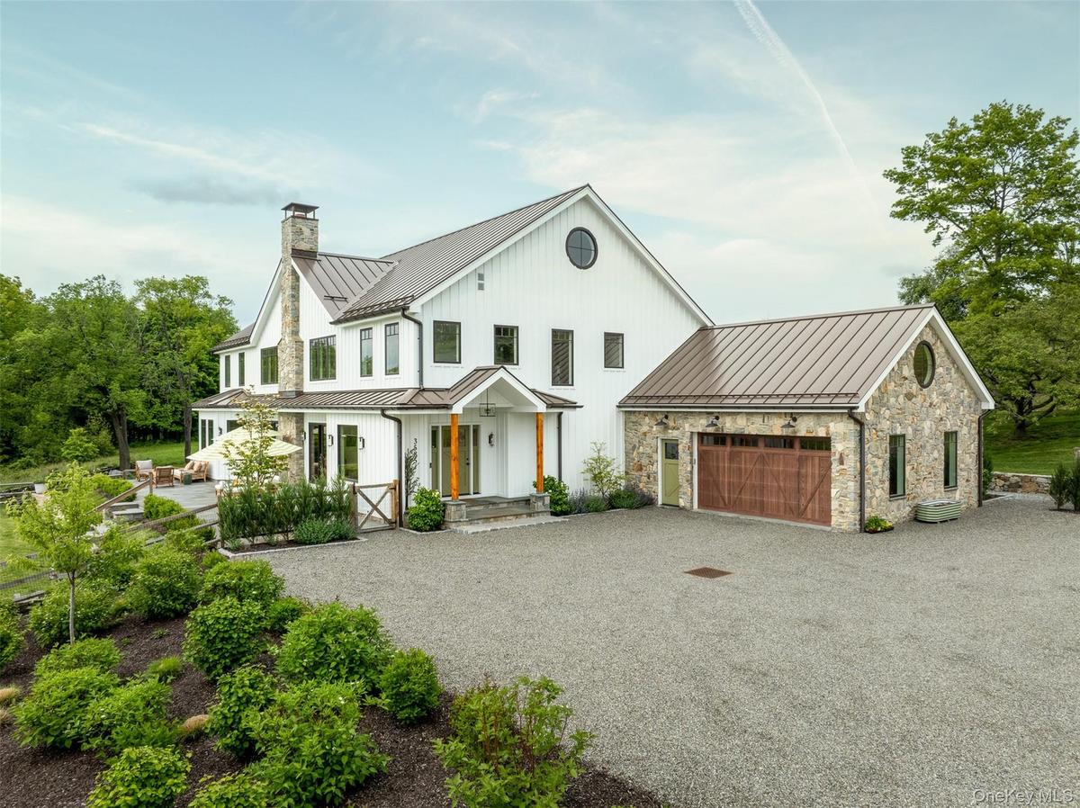 Modern farmhouse style home with a standing seam roof, a chimney, metal roof, driveway, and an attached garage
