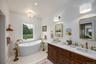 Full bath with baseboards, double vanity, a freestanding bath, and ensuite bath