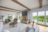 Living room with beamed ceiling, a stone fireplace, wood finished floors, and recessed lighting