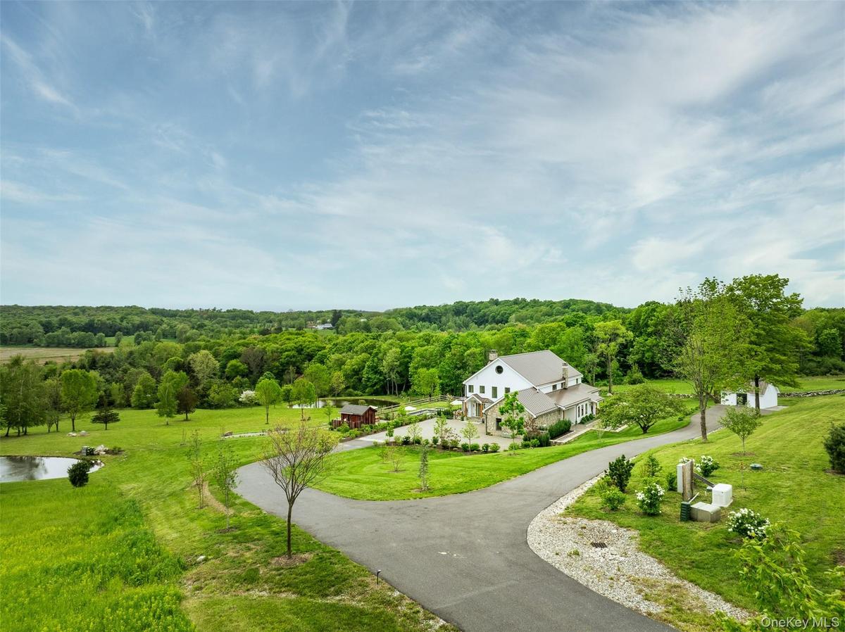 View of property's community featuring curved driveway, a water view, a wooded view, and a lawn