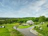 View of property's community featuring curved driveway, a water view, a wooded view, and a lawn