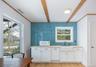 Bar area featuring white cabinets, white microwave, light wood finished floors, decorative molding, and tiled walls