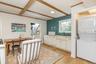 Laundry area featuring light wood-style floors, stacked washer and clothes dryer, and beam ceiling