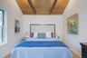 Bedroom with wood ceiling, wooden walls, lofted ceiling with beams, and light wood-style flooring