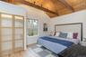 Bedroom with wooden ceiling, light wood finished floors, and vaulted ceiling with beams
