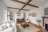 Living area with a fireplace with flush hearth, beamed ceiling, baseboards, wood finished floors, and recessed lighting
