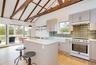 Kitchen with high end range, light wood-style floors, a kitchen island, lofted ceiling, and a breakfast bar