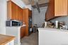 Kitchen featuring brown cabinetry, light countertops, finished concrete floors, freestanding refrigerator, and stainless steel microwave
