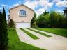 View of property exterior with brick siding, a garage, concrete driveway, and a yard