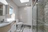 Full bath with tile walls, a skylight, vanity, and a stall shower