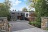 A private approach - introduces the home's modern facade through stone pillars and circular driveway