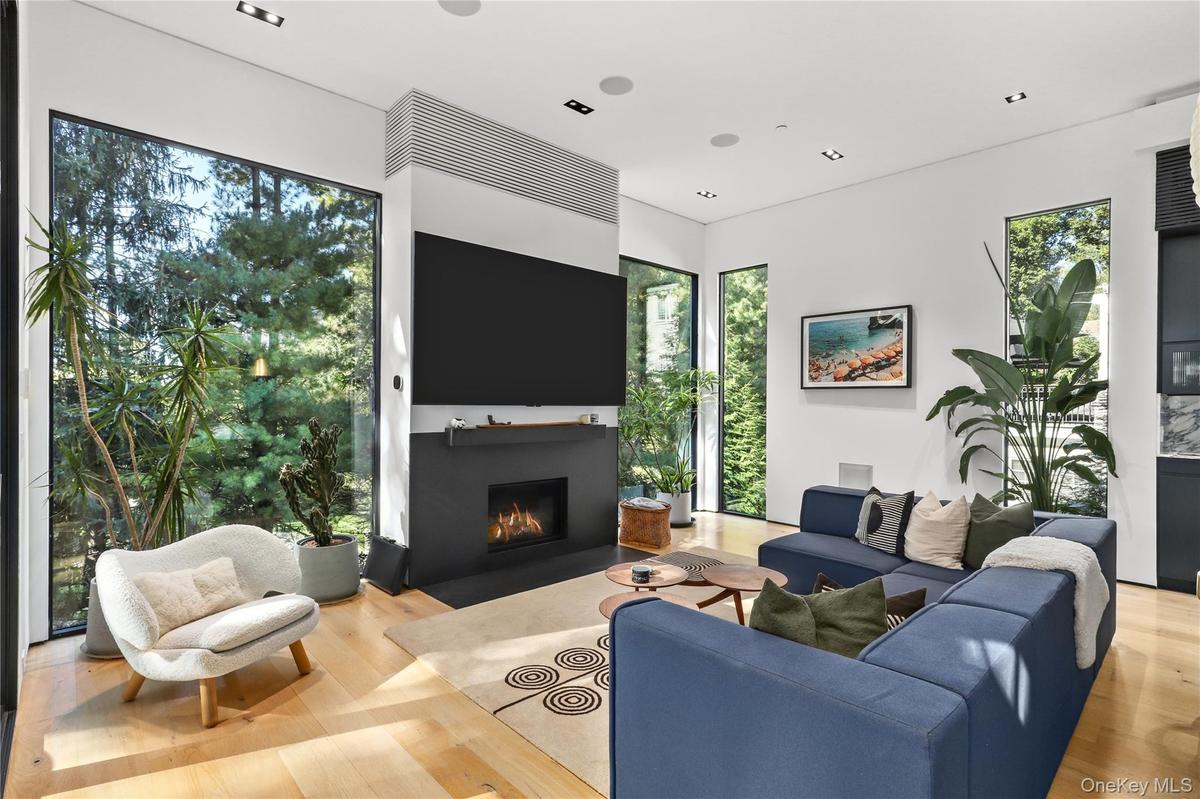 Living Room – Sleek gas fireplace with stone mantel and built-in media wall, oversized windows creates a warm modern retreat
