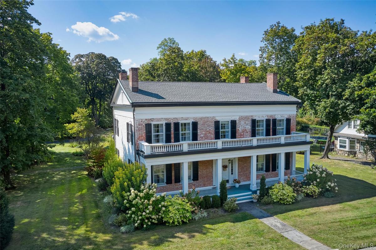 View of front of property featuring a front yard, brick siding, a porch, and a chimney