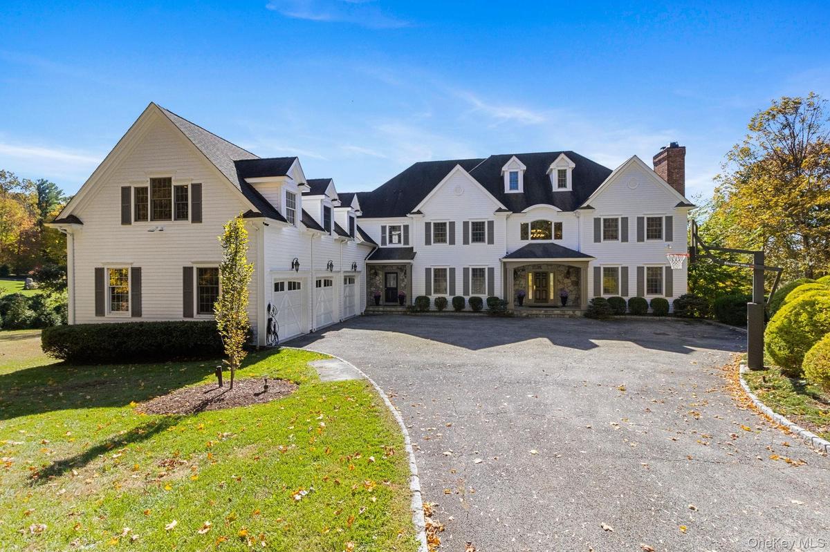 Traditional home featuring asphalt driveway, a front lawn, and a chimney