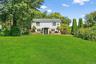 Colonial house featuring a front lawn and view of scattered trees
