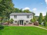 Colonial-style house featuring roof with shingles
