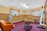 Living area with a baseboard heating unit, a wainscoted wall, carpet flooring, and wood walls