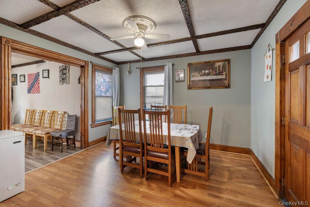 Dining space with a textured ceiling, light wood-type flooring, beam ceiling, ceiling fan, and coffered ceiling
