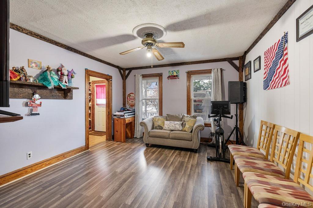 Living room featuring a textured ceiling, ceiling fan, ornamental molding, and dark hardwood / wood-style floors