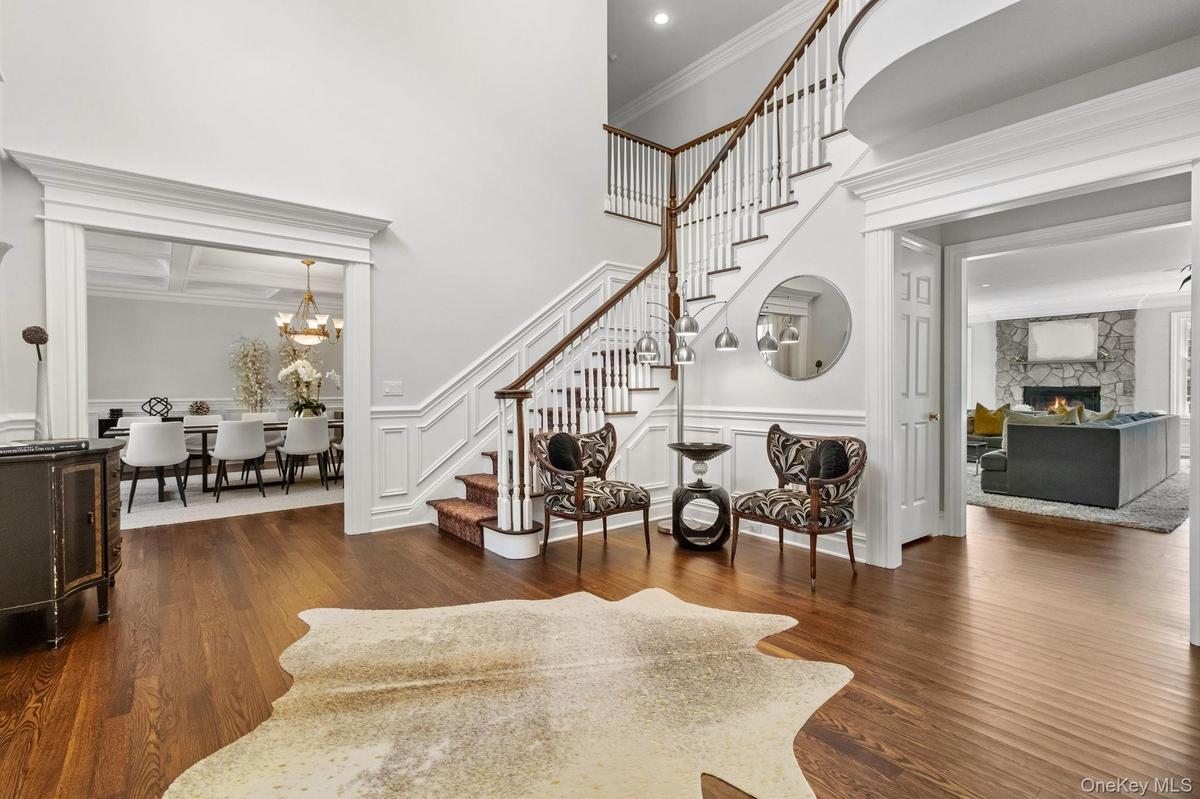 Entryway featuring stairway, dark wood-type flooring, a stone fireplace, ornamental molding, and a chandelier