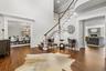 Entryway featuring stairway, dark wood-type flooring, a stone fireplace, ornamental molding, and a chandelier
