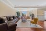 Living area with hardwood / wood-style flooring, crown molding, a raised ceiling, a wainscoted wall, and recessed lighting