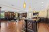Kitchen featuring dark countertops, crown molding, a kitchen breakfast bar, decorative light fixtures, and dark brown cabinets