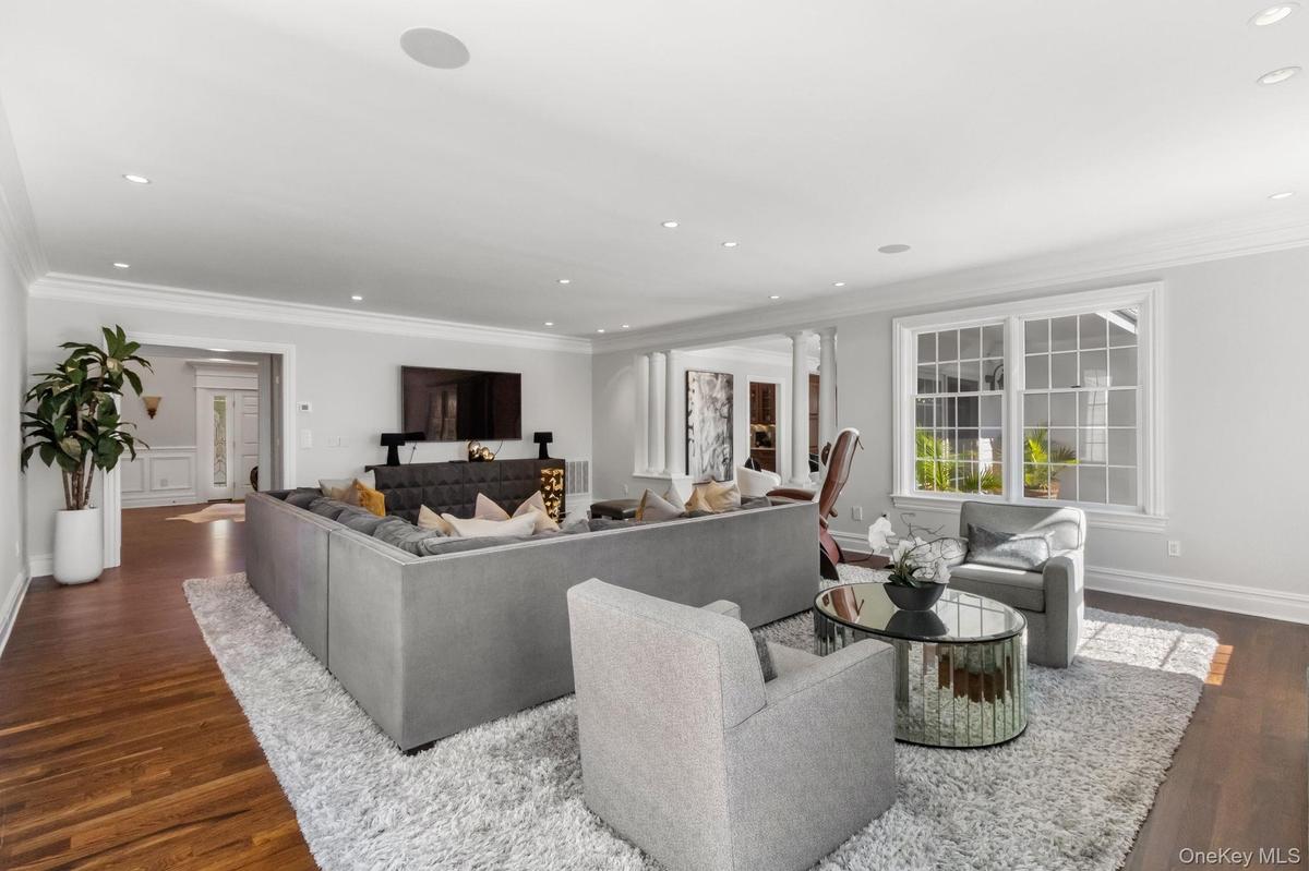 Living room with ornamental molding, dark wood-type flooring, and recessed lighting