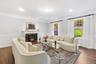 Living room featuring a high end fireplace, dark wood-style floors, ornamental molding, a decorative wall, and wainscoting