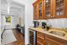 Bar area featuring light stone countertops, coffered ceiling, beverage cooler, beam ceiling, and ornamental molding