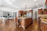 Kitchen featuring glass insert cabinets, backsplash, light stone counters, recessed lighting, and hanging light fixtures