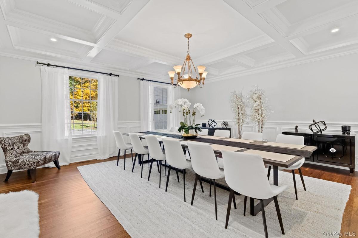 Dining space featuring a decorative wall, beam ceiling, a wainscoted wall, a chandelier, and wood finished floors