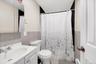 Bathroom with vanity, tile walls, a baseboard radiator, a wainscoted wall, and shower / bathtub combination with curtain