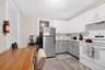 Kitchen with white range with electric stovetop, light countertops, freestanding refrigerator, white cabinetry, and gray cabinets