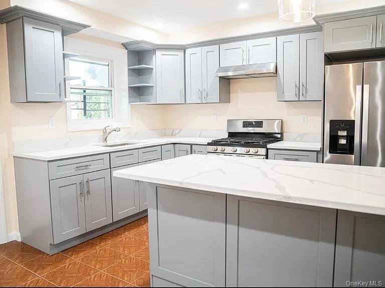 Kitchen with open shelves, a sink, appliances with stainless steel finishes, gray cabinetry, and under cabinet range hood
