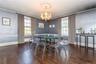 Dining area with dark wood-type flooring, an inviting chandelier, and ornamental molding