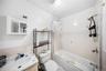 Full bath featuring shower / bath combo, vanity, tile walls, and wainscoting