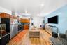 Kitchen featuring open floor plan, stainless steel appliances, backsplash, brown cabinets, and dark countertops