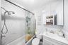 Bathroom with vanity, bath / shower combo with glass door, and a wainscoted wall