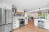 Kitchen featuring stainless steel appliances, white cabinets, open floor plan, a warm lit fireplace, and ornamental molding